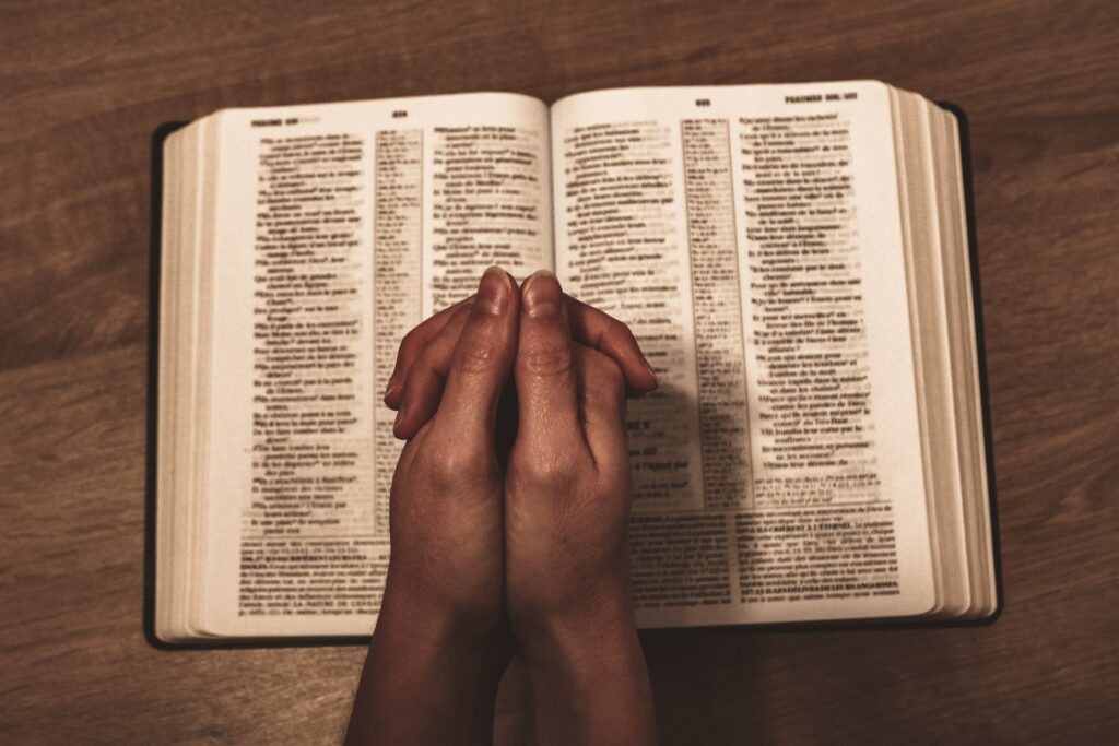 Open Bible with praying hands