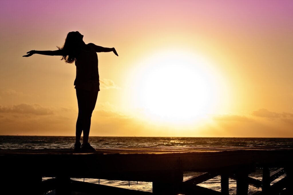 Woman with arms outstretched at sunset, happy