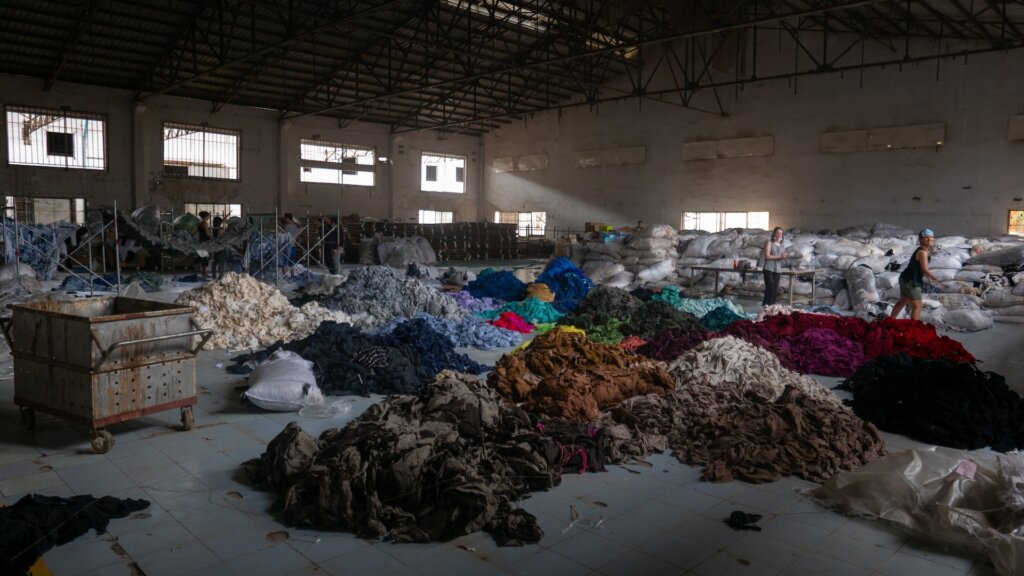 Piles of clothes in factory - Fast Fashion